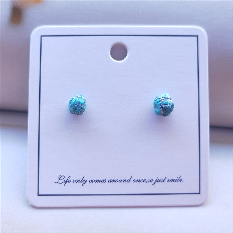 Turquoise stud earrings on a white card with a motivational quote.