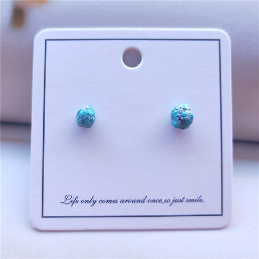 Turquoise stud earrings on a white card with a motivational quote.