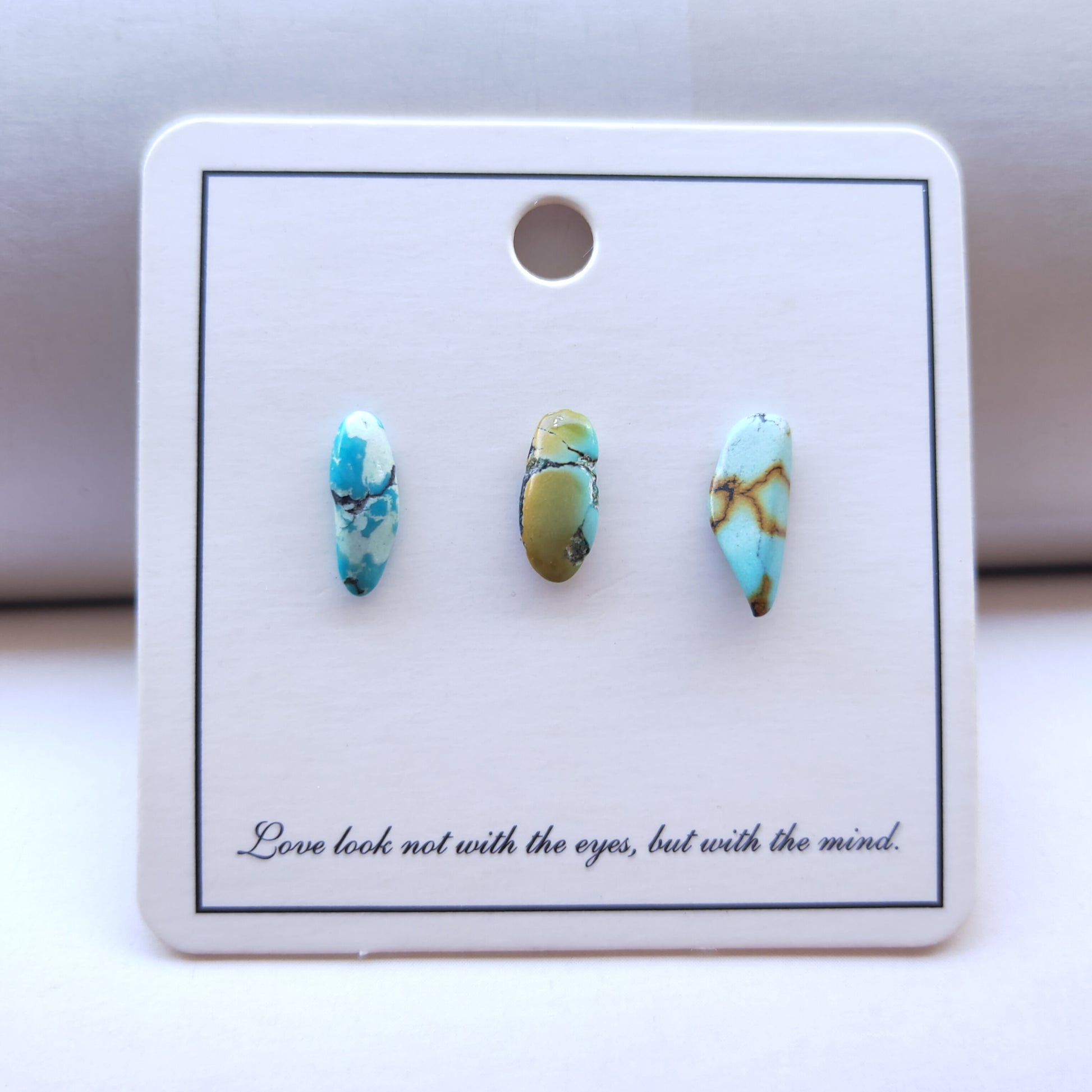 Turquoise stone earrings on a display card with a quote.