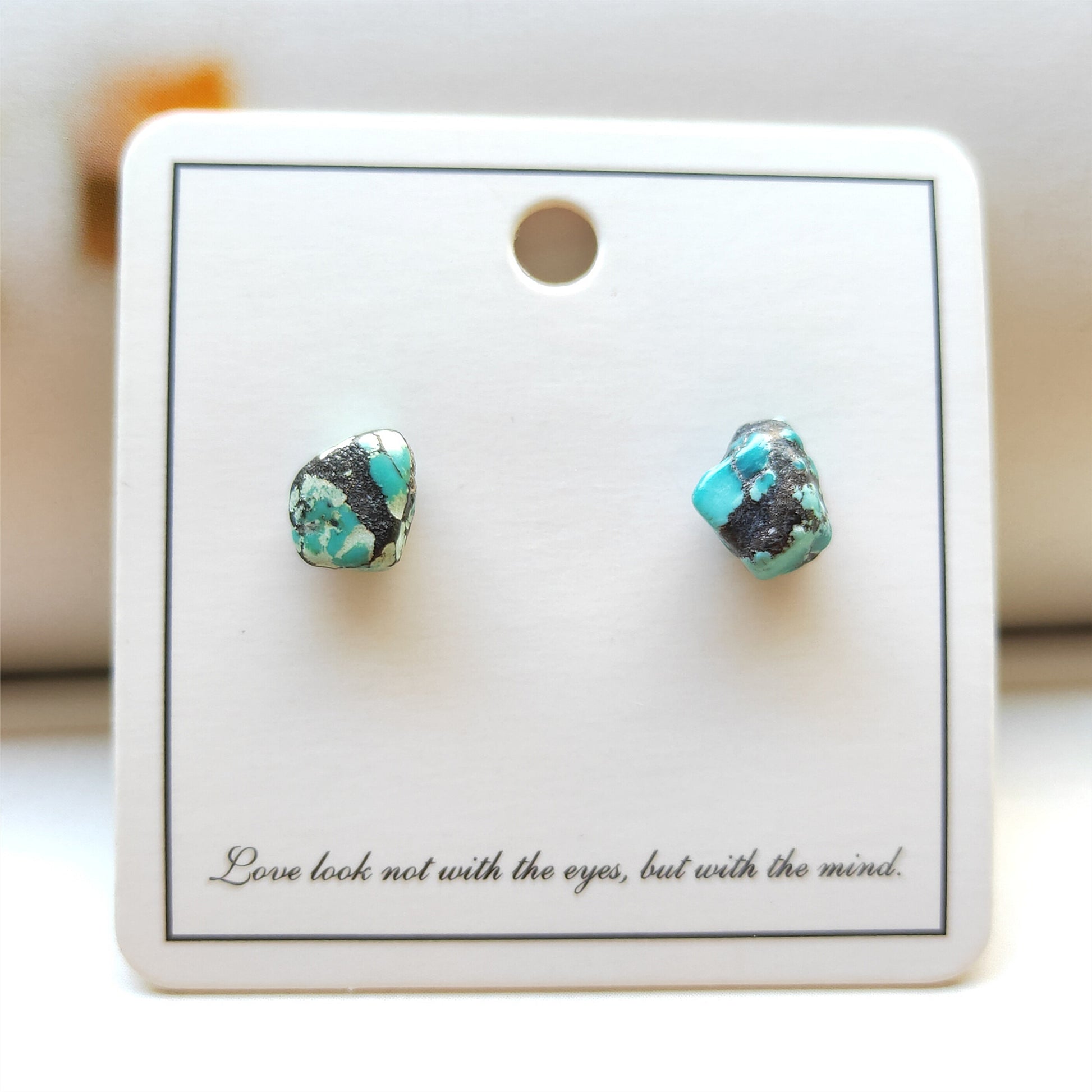 Turquoise stone stud earrings on a display card with text.